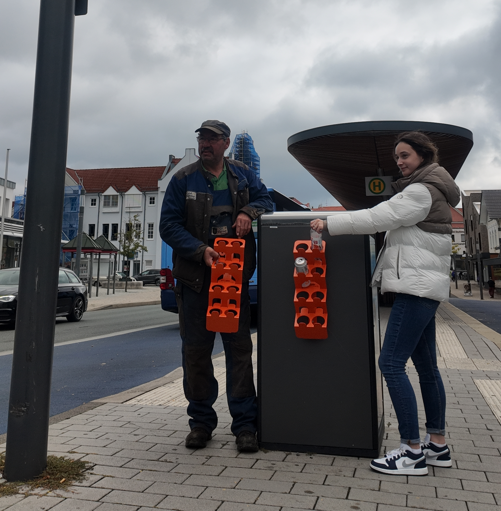 Pfandflaschenhalterungen werden an einem der smarten Mülleimer von Mitarbeitern des Bauhofs und des Bauamts angebracht.